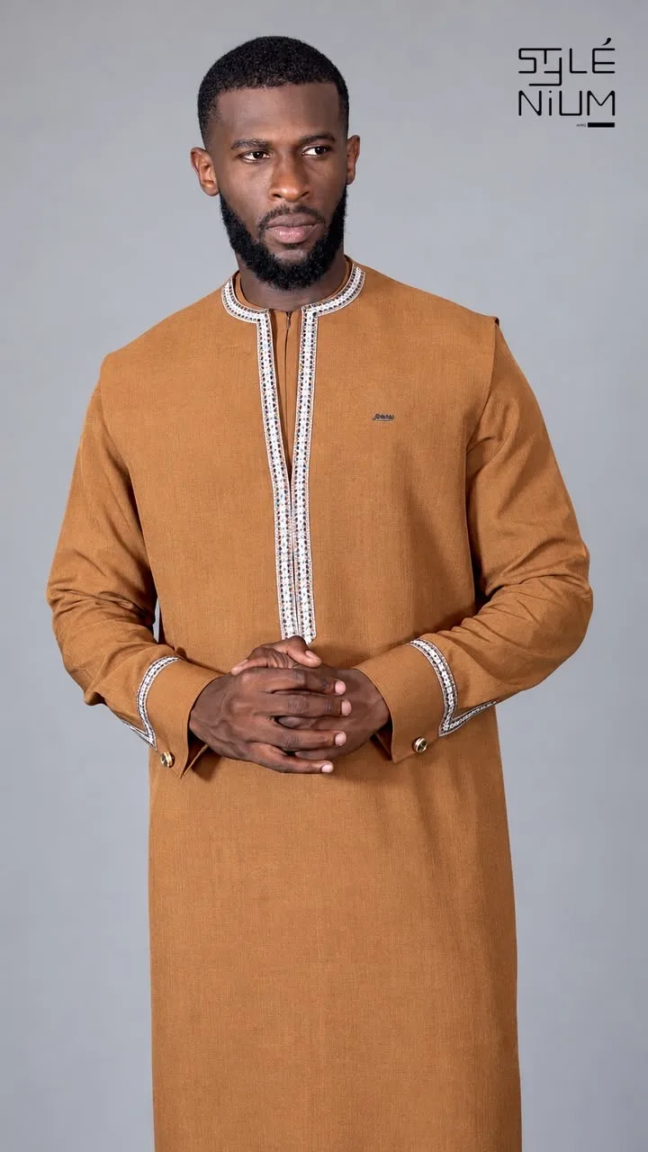 Homme portant un long boubou camel orné de galons brodés blancs à motifs à l'encolure, au plastron et aux poignets, création AMG STYLENIUM
